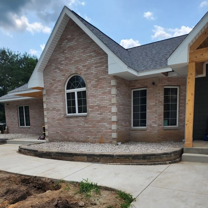 Exterior curved retaining wall durable decorative stone home upgrades — completed by 848 Property Services in Hastings, MI.
