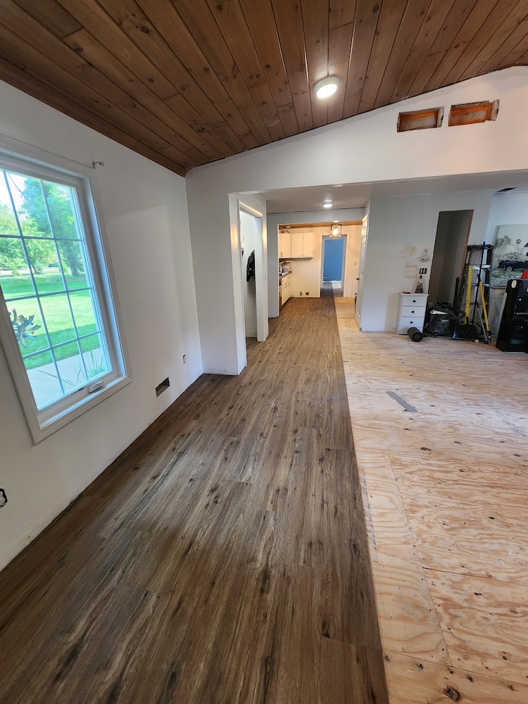 Interior wood flooring installation half living room home remodel — completed by 848 Property Services in Hastings, MI.